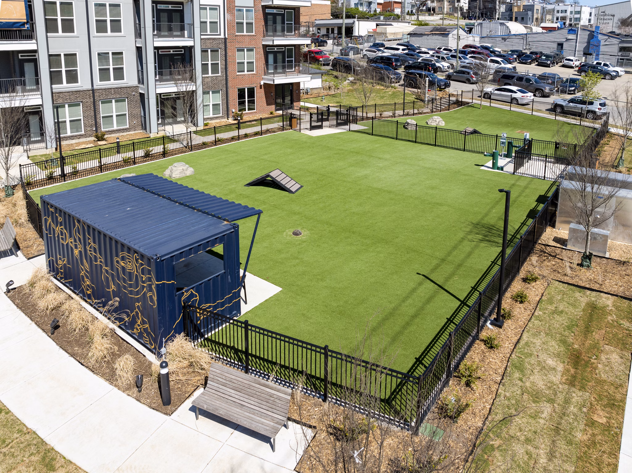 Dog park area with artificial grass, benches, and agility equipment at luxury apartments
