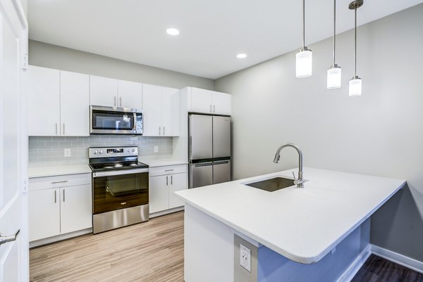 Modern kitchen with stainless steel appliances and island at The Pointe at Siena Ridge Apartments