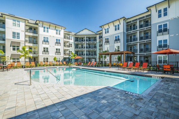 Resort-style pool at The Pointe at Siena Ridge Apartments, a luxury Greystar property offering sun loungers and lush landscaping