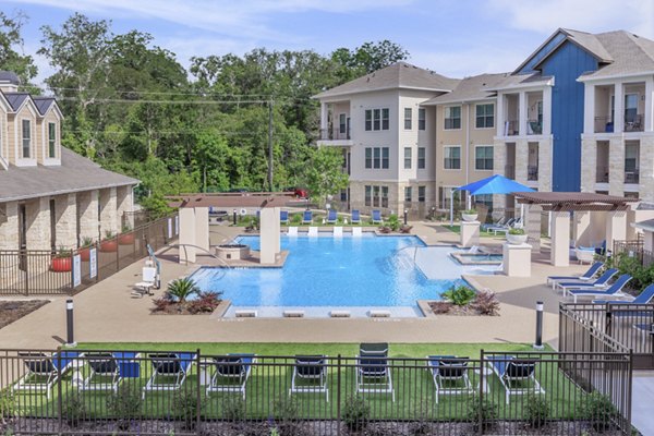 Serene pool at Reserve at Lake Jackson Apartments with lush surroundings and lounge chairs
