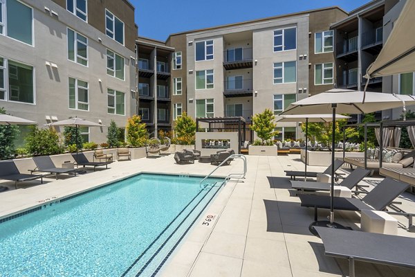 Relax by the outdoor pool featuring lounge chairs at The Hayden Apartments, a luxury living space by Greystar