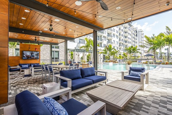 Modern pool patio at Overture Doral Apartments with elegant lounge chairs and lush landscaping, offering a luxurious outdoor living space