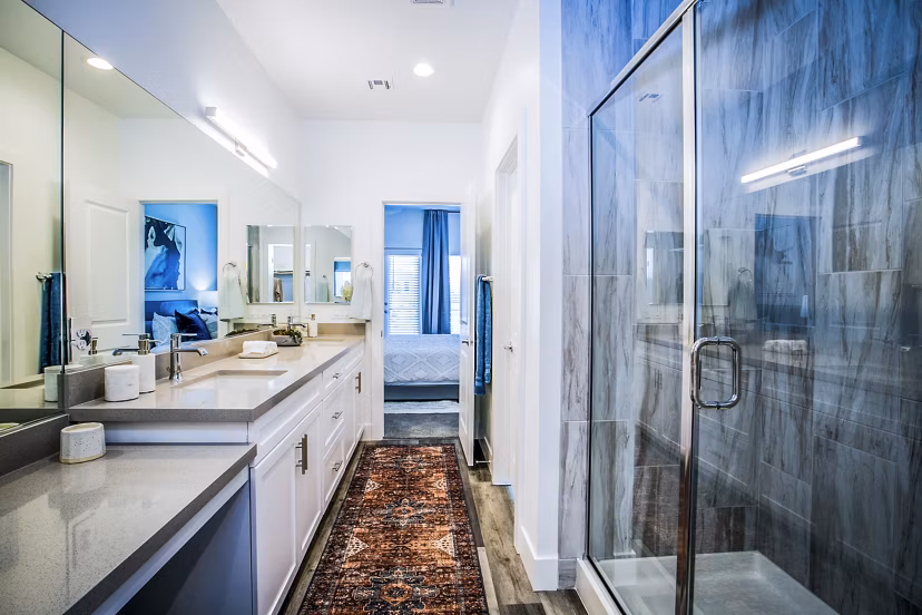 Elegant bathroom with marble countertops and lighted vanity in Townes at Peace Way Apartments
