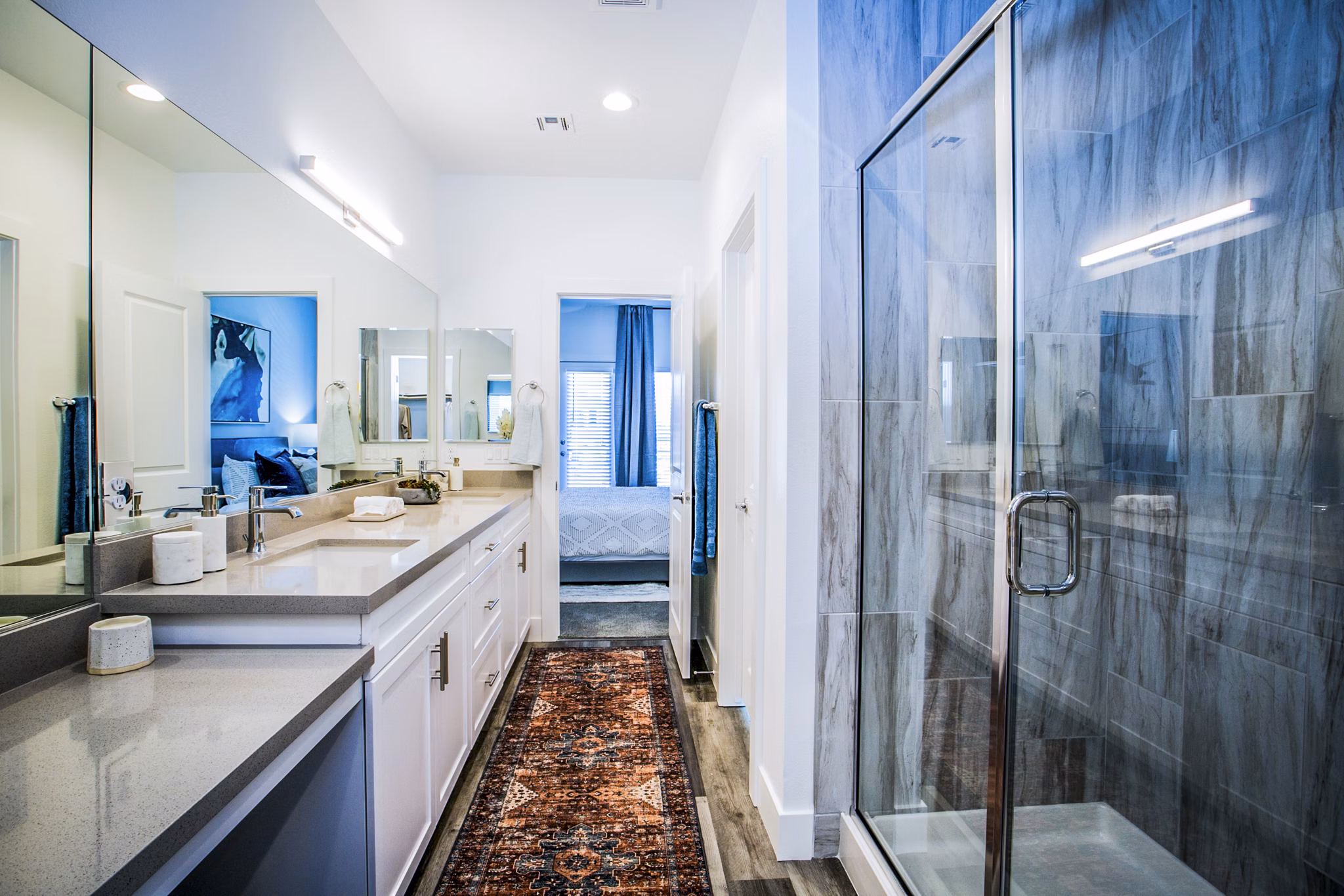 Elegant bathroom with marble countertops and lighted vanity in Townes at Peace Way Apartments