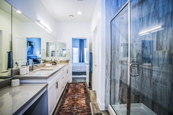 Elegant bathroom with marble countertops and lighted vanity in Townes at Peace Way Apartments