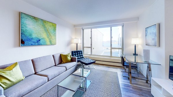 Spacious living room with skyline views at 1000 Chestnut Apartments, a Greystar luxury community