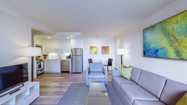 Spacious living room with modern furnishings at 1000 Chestnut Apartments, featuring large windows and elegant decor