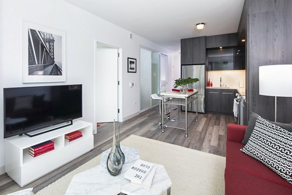 Living room featuring modern decor and large windows at 1177 Market Apartments, a luxury property by Greystar