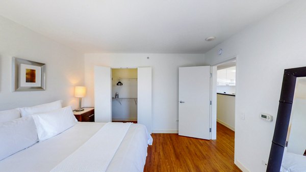 Bedroom featuring modern design with cozy bedding and large windows in 1188 Mission Apartments