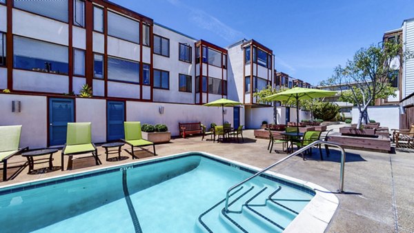Relaxing outdoor pool area at 230 Dolores Apartments, featuring luxurious lounge seating and serene garden surroundings for Greystar residents