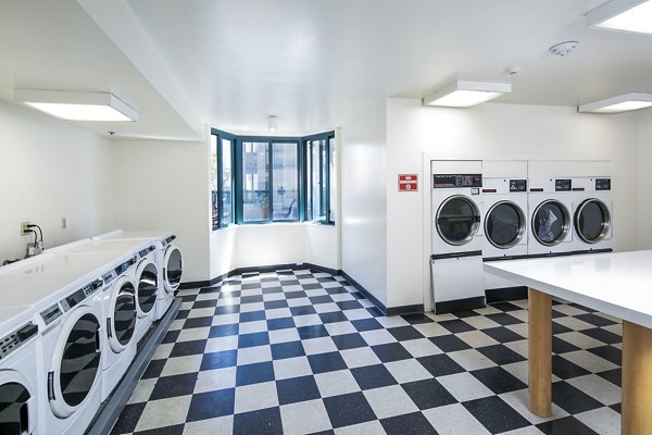 Laundry room with modern machines at Trinity Towers Apartments offering convenient amenities for residents