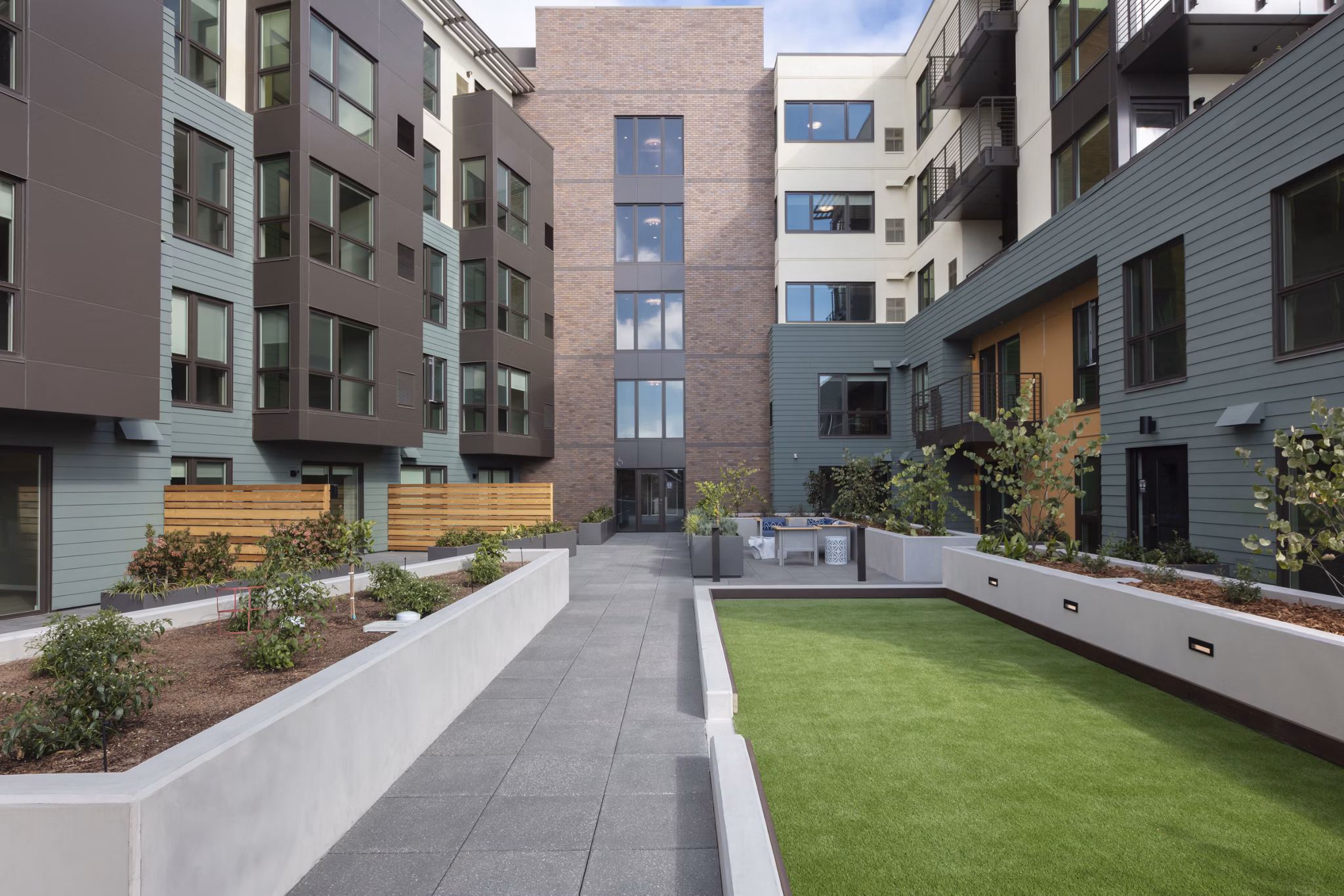 Courtyard featuring lush greenery and seating at Baxter on Broadway Apartments