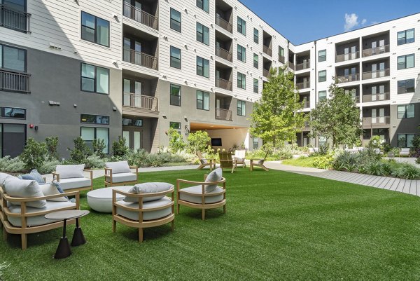 Recreational area with lounge chairs and outdoor grills at Solomon Apartments