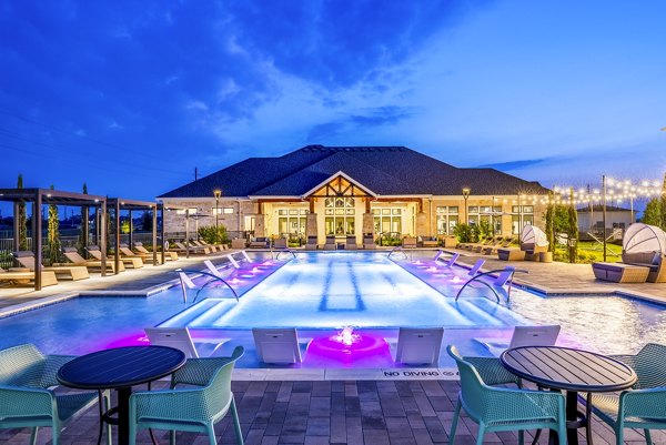 Inviting pool area at Allora Alamo Heights Apartments featuring stylish lounging chairs and lush palm trees