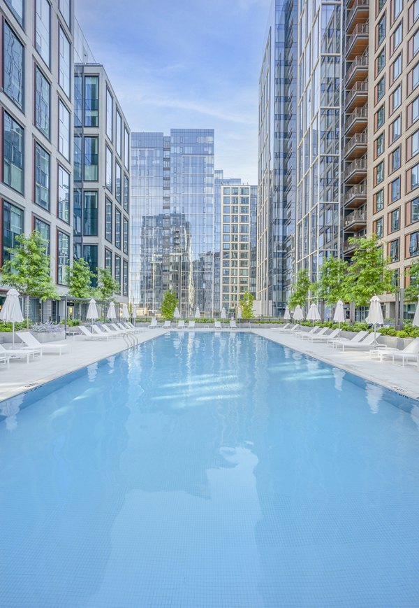 Resort-style pool with elegant lounge chairs at The Alyx Apartments, a luxury living community in vibrant cityscape