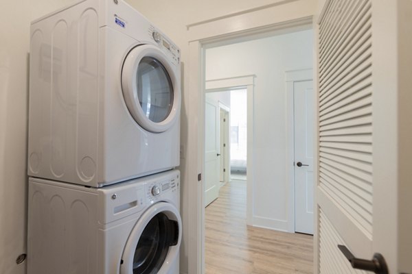 Laundry room with modern machines at Harrison Yards Apartments offering convenience to residents