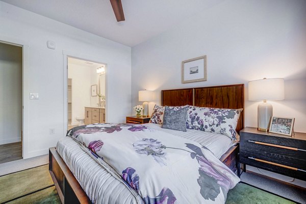 Spacious bedroom with modern furnishings in Reveal Apartments, featuring elegant decor and ample natural light