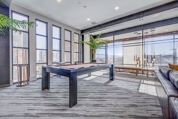 Clubhouse game room featuring a billiards table and lounge seating at Reveal Apartments luxury community