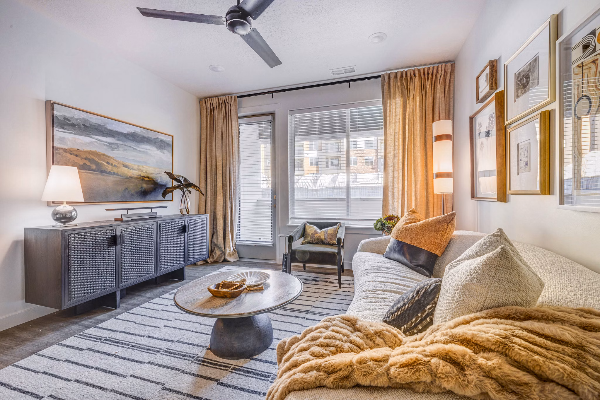 Reveal Apartments: Sunlit living room with modern furnishings, hardwood floors, and large windows creating an inviting space