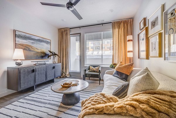 Reveal Apartments: Sunlit living room with modern furnishings, hardwood floors, and large windows creating an inviting space