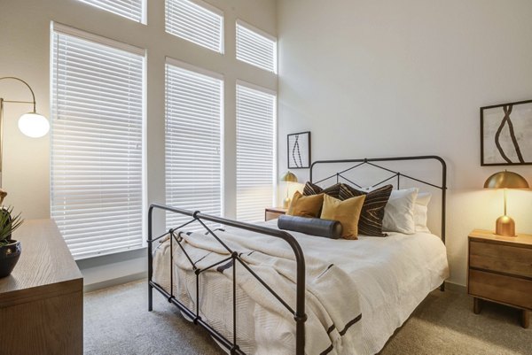 Elegant bedroom featuring modern decor and large windows in NOMA Apartments, Greystar luxury living