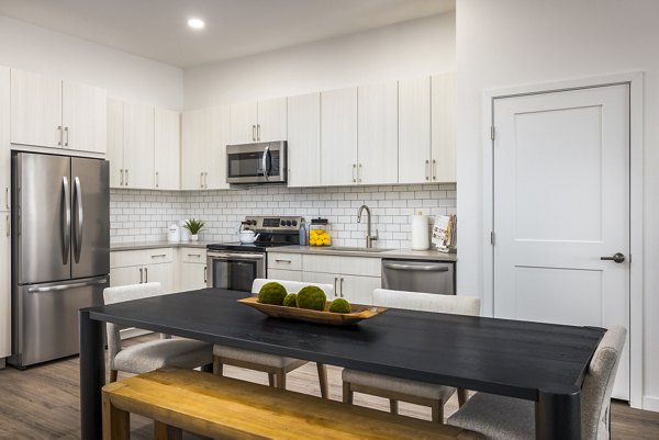 Open-concept kitchen and dining room with modern appliances in Braxton Apartments, a luxury community by Greystar