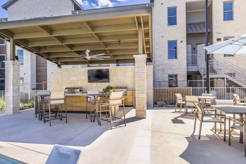 Outdoor grill area with modern patio seating at The Chloe Leander Apartments, perfect for gatherings and relaxation