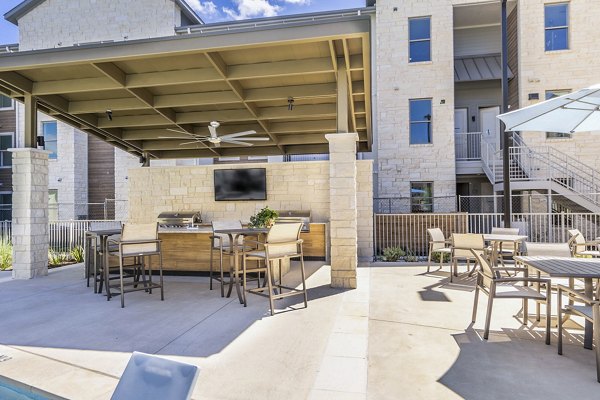 Outdoor grill area with modern patio seating at The Chloe Leander Apartments, perfect for gatherings and relaxation