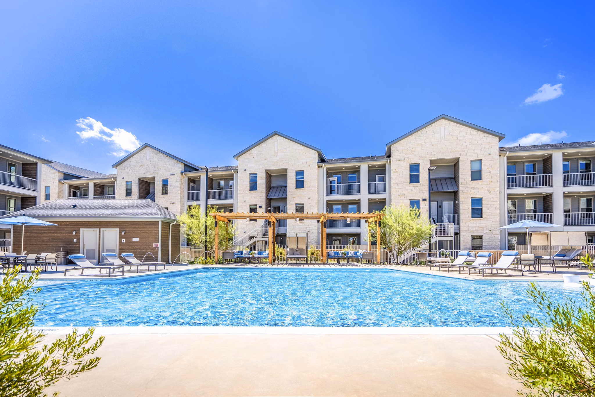 Poolside oasis at The Chloe Leander Apartments featuring resort-style seating and palm trees