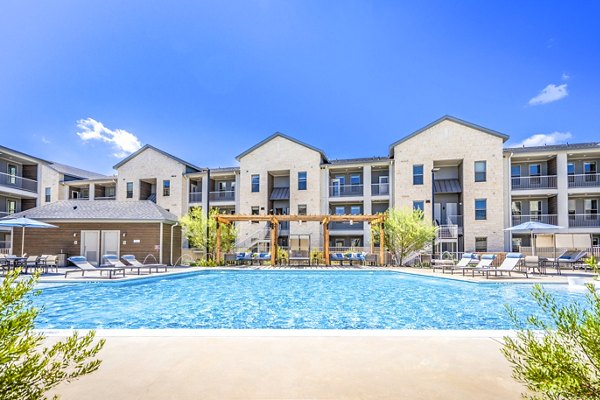 Poolside oasis at The Chloe Leander Apartments featuring resort-style seating and palm trees