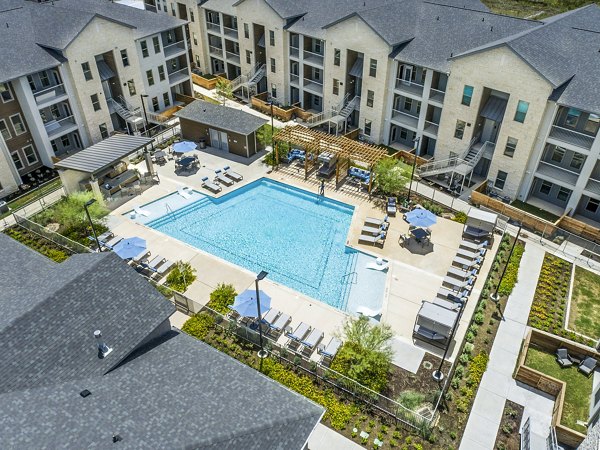 Resort-style pool with lounge chairs at The Chloe Leander Apartments, offering luxury living in a serene setting