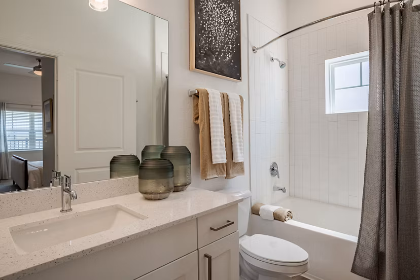 Bathroom with sleek fixtures and large mirrors at Eden Heritage Lakes Apartments, luxury residential community