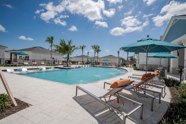 Resort-style pool at Bay Court at Eden Heritage Lakes Apartments, featuring sun loungers and lush landscaping for relaxation