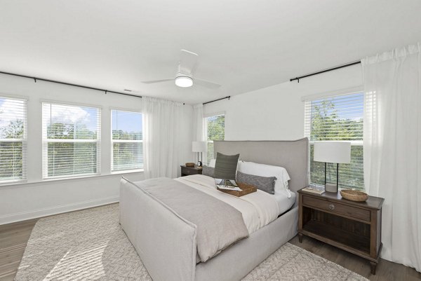 Cozy bedroom with modern furnishings at Affinity at Hudson Apartments, a luxury Greystar community