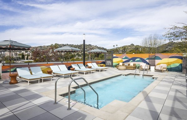 Pool with lounge chairs and palm trees at The Charlie WeHo: luxury apartments in West Hollywood