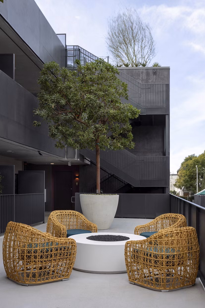 The Charlie WeHo Apartments: Serene courtyard featuring lush greenery and outdoor seating in West Hollywood