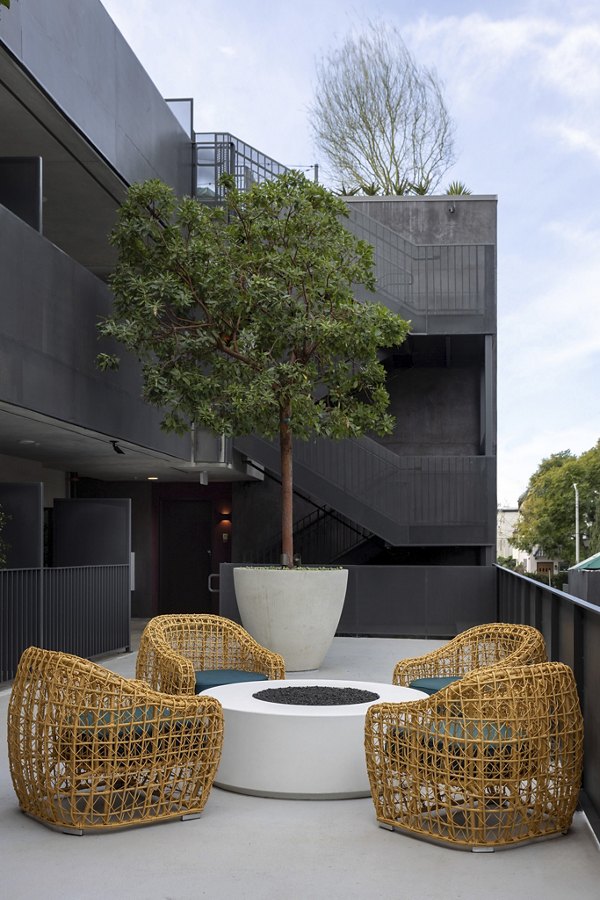 The Charlie WeHo Apartments: Serene courtyard featuring lush greenery and outdoor seating in West Hollywood