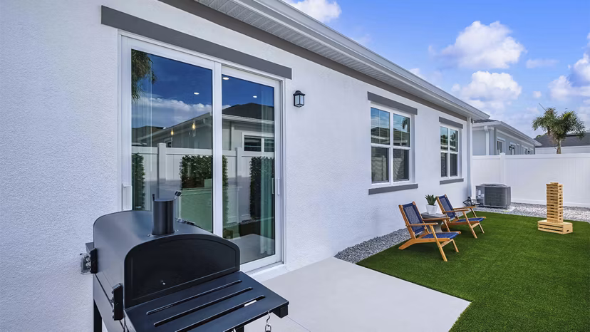 Patio space with cozy seating and lush greenery at Yardly Artisan Lakes Homes, ideal for relaxing and entertaining