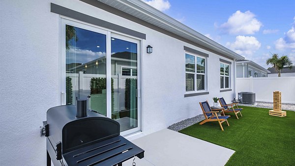 Patio space with cozy seating and lush greenery at Yardly Artisan Lakes Homes, ideal for relaxing and entertaining