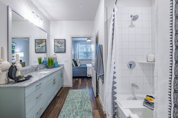 Modern bathroom featuring sleek fixtures and large mirror at Prose Stoneridge Apartments