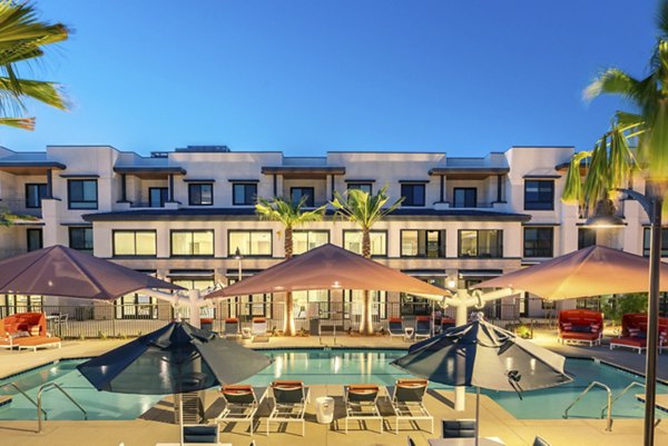 Avenida Palm Desert: Luxurious pool with surrounding palm trees and lounge chairs at Avenida Palm Desert Apartments