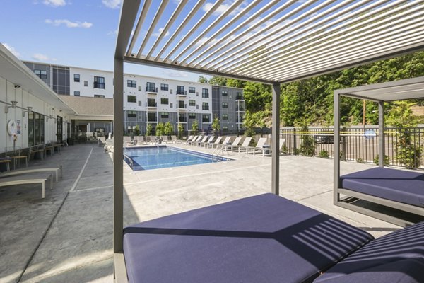Relaxing outdoor pool at The Foundmore Apartments with lounge seating and greenery, offering a luxury retreat in a vibrant community setting