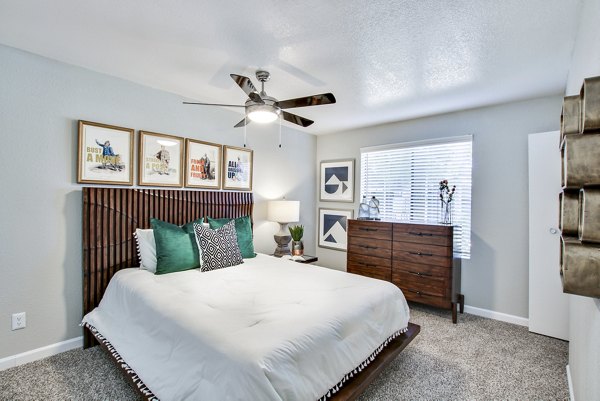 Modern bedroom with stylish decor, ceiling fan, and framed artwork in luxury apartments