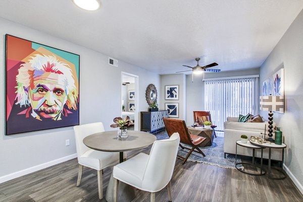 Modern living and dining area featuring round table and colorful portrait in luxury apartment