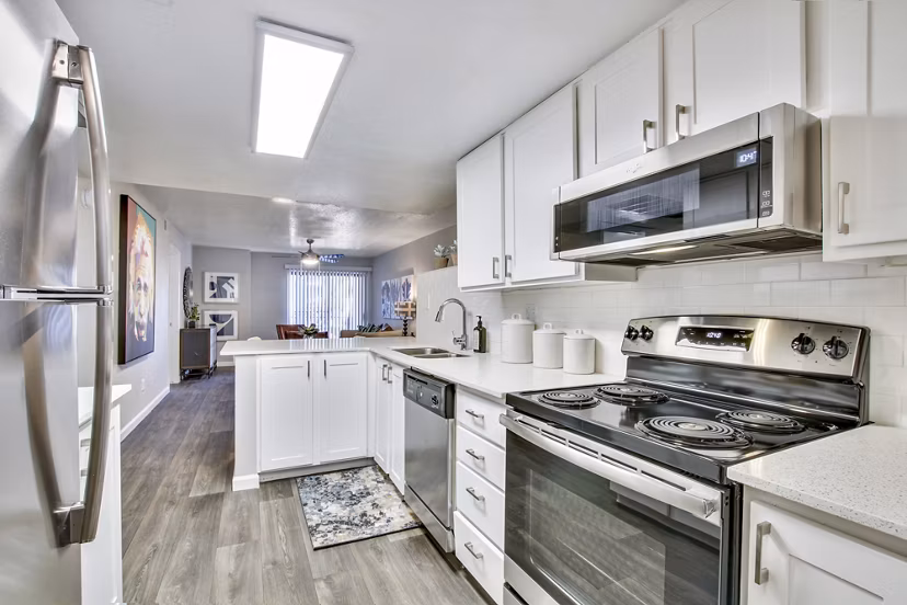 Modern kitchen featuring white cabinets and stainless steel appliances in luxury apartment
