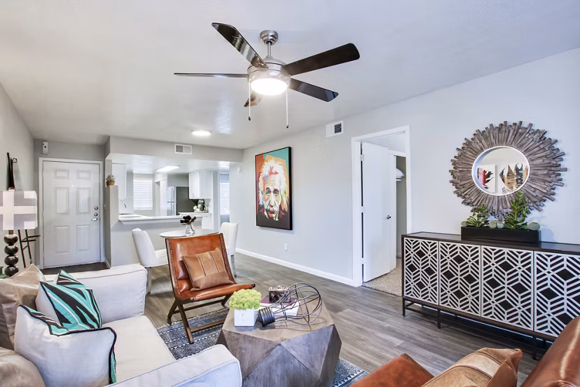 â€œModern living room with a ceiling fan, seating area, and decorative mirror in luxury apartmentsâ€