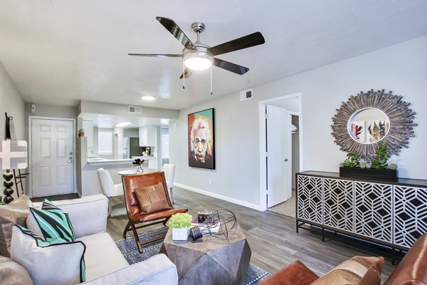 â€œModern living room with a ceiling fan, seating area, and decorative mirror in luxury apartmentsâ€