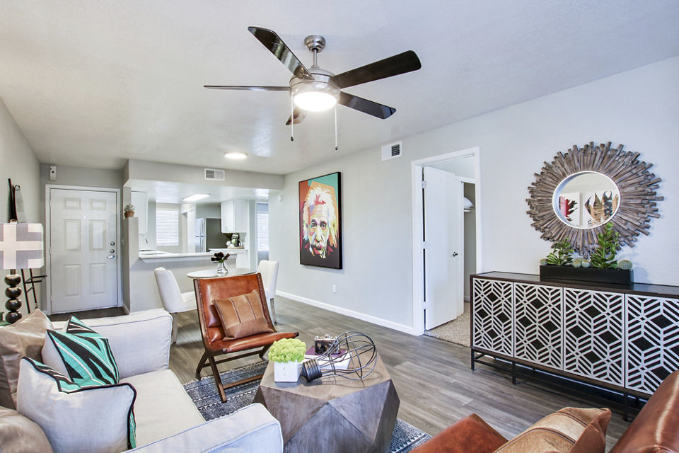 â€œModern living room with a ceiling fan, seating area, and decorative mirror in luxury apartmentsâ€