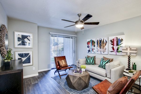 Modern living room featuring a ceiling fan, stylish sofa, and decorative plants in luxury apartments