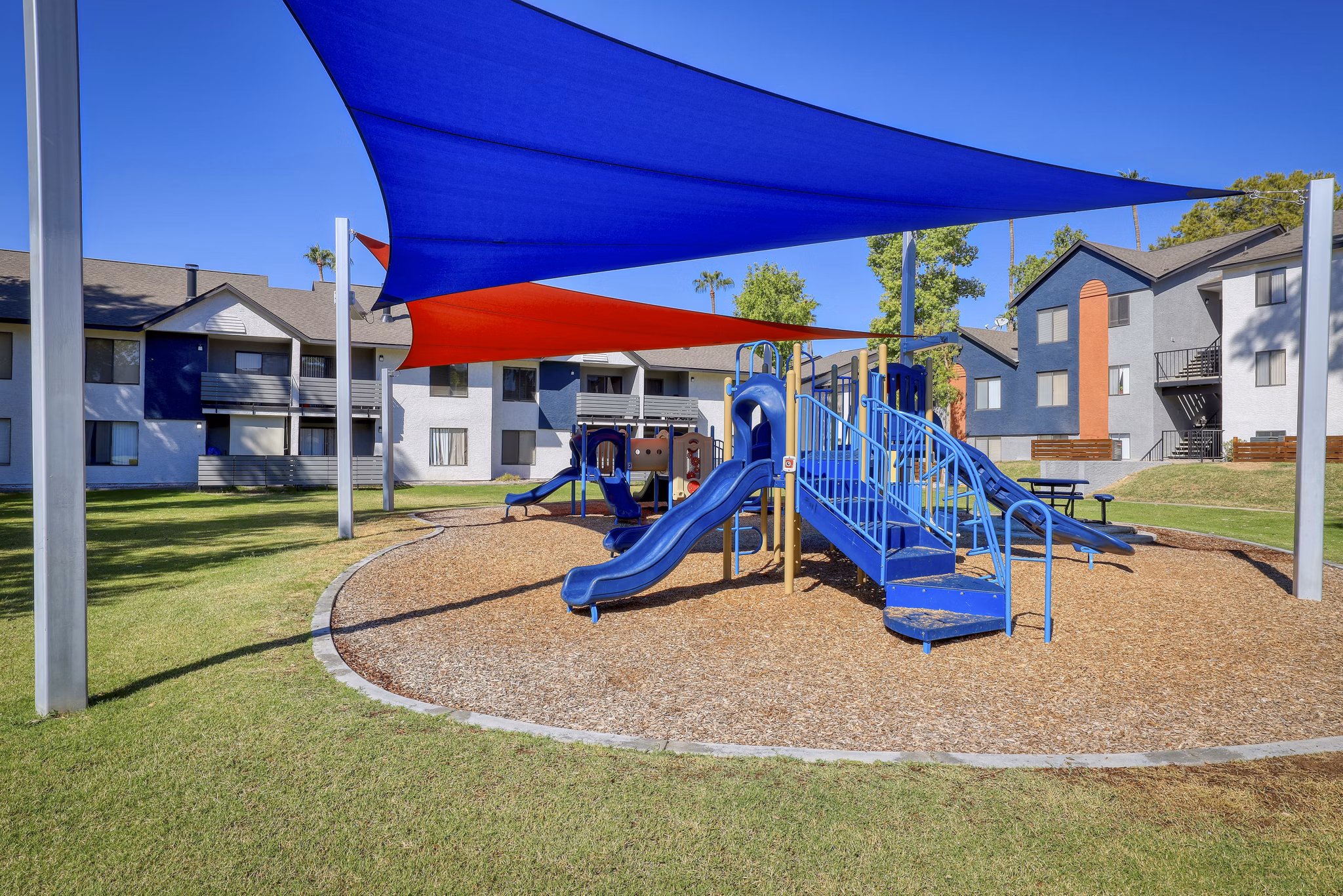 Playground with slides and swings at The Julia Apartments, a family-friendly amenity perfect for children to enjoy outdoor play